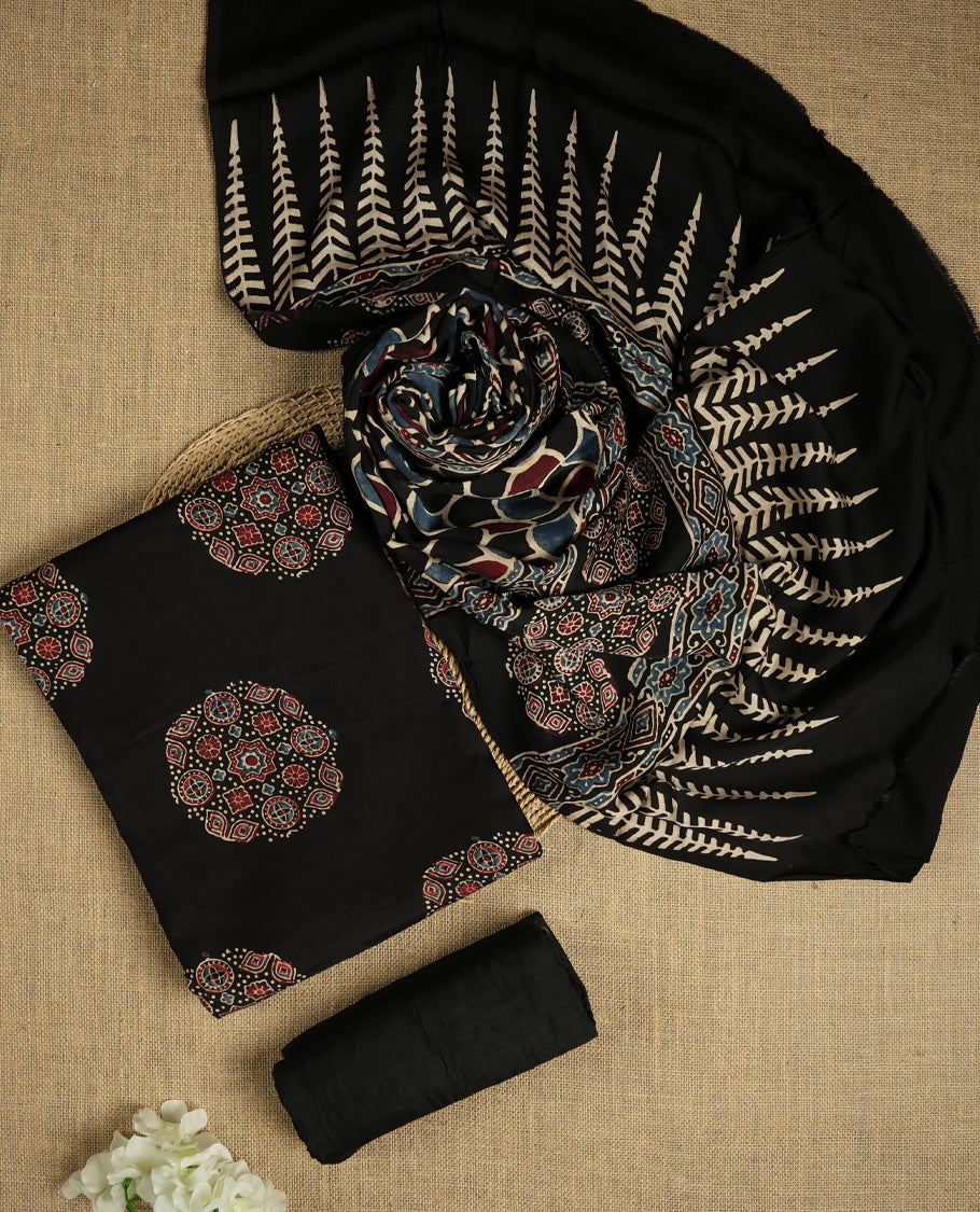Black suit material featuring intricate Ajrak inspired prints in maroon, blue, and beige & Includes a beautifully patterned dupatta and matching plain bottom.
