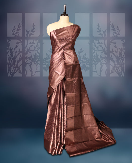 Copper brown semi silk brocade saree adorned with subtle self brocade patterns and a sleek matching woven border and pallu, Comes with a coordinated blouse, perfect for understated traditional elegance.