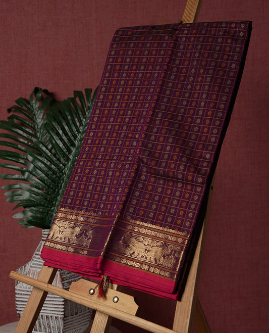 Maroon colour pure Kanchi cotton saree featuring golden checks with floral motifs, enhanced by a grand zari border woven with majestic elephant patterns, exuding elegance and tradition & Comes with matching blouse.