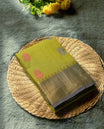 Olive yellow colour silk cotton saree with delicate floral motifs on the body, complemented by a shimmering golden zari border and a graceful pallu & Comes with a matching blouse piece for a perfect traditional look.