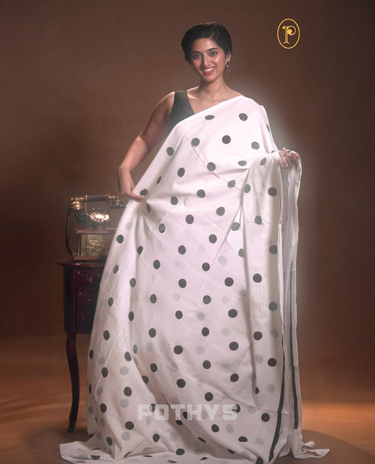 White with black colour Mul cotton saree featuring polka dot prints across the body, accented with a subtle small border, without a blouse piece.