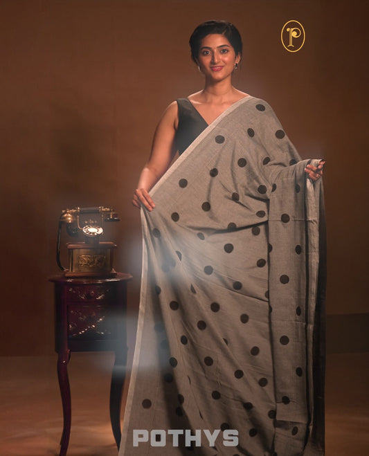 Grey colour Mul cotton saree featuring polka dot prints across the body, accented with a subtle small border, without a blouse piece.