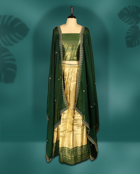 Elegant Semi stitiched green and gold Dhavani set featuring a lustrous gold skirt with intricate zari weave and matching green border, paired with a deep green dupatta embellished with delicate zari motifs for a regal look