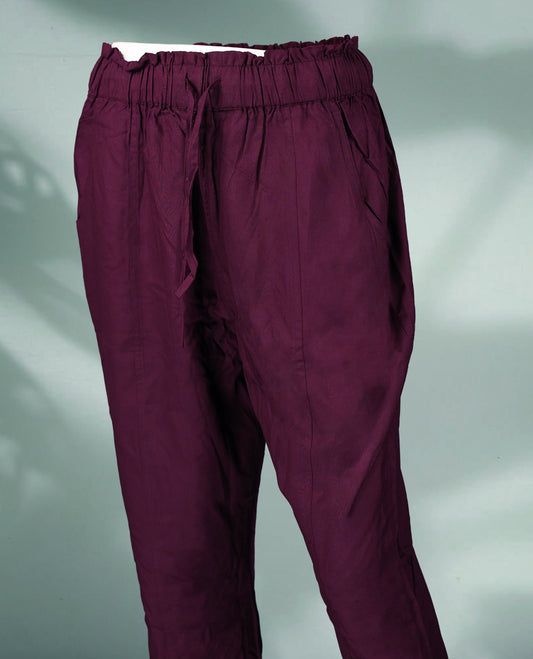 Deep plum colour women's pants feature an elasticated waistband with a drawstring, side pockets, and a relaxed ankle length fit