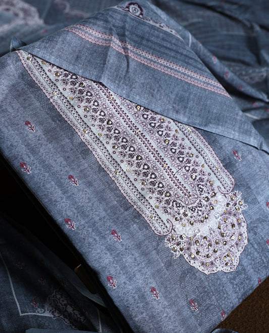 Denim blue colour churidhar material with intricate white and silver embroidery on the neckline, paired with a coordinated printed dupatta and plain bottom.