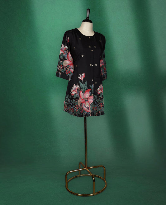 Black colour short kurti featuring a round neck and three quarter sleeves, adorned with soft golden motifs and a vibrant floral print along the hem and sleeves for a bold, elegant finish.