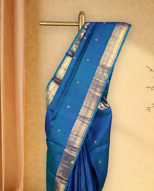 Peacock blue colour pure Kancheepuram saree with gold zari symmetrical motifs, traditional border with peacock and chakra designs, grand pallu with diamond motifs, and matching blouse.