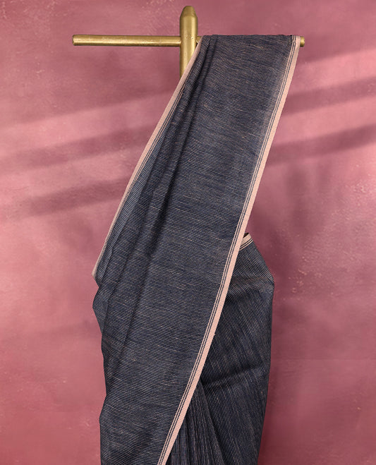 Deep navy blue colour pure linen saree featuring fine beige thread stripes running throughout the body, accented with a soft beige border and pairs gracefully with a matching blouse.