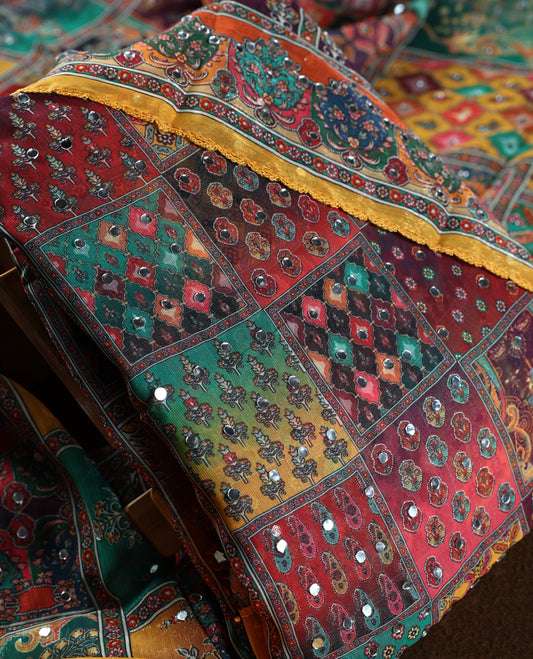 Yellow colour churidhar material with vibrant multicolour geometric and paisley prints, enhanced with delicate mirror work, paired with a plain matching bottom and bold printed dupatta, perfect for festive occasions.