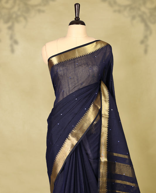 Navy Blue colour Chanderi cotton saree featuring a subtly textured body with delicate buti work, complemented by a rich golden zari border with matching blouse