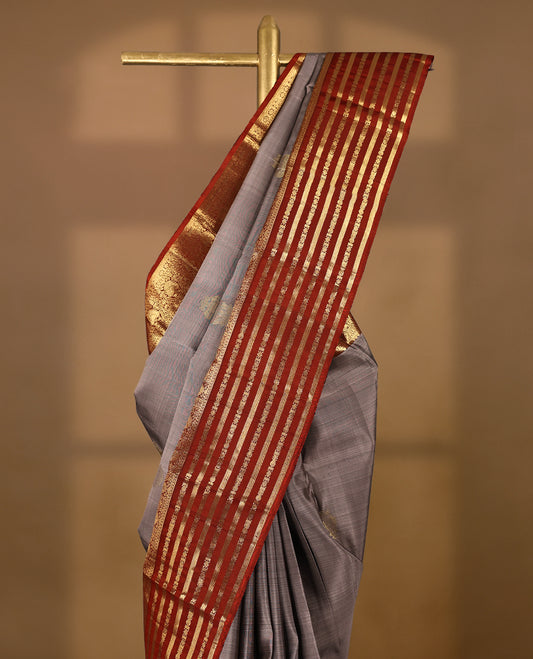 Muted lavender-grey  Colour traditional Kancheepuram silk saree adorned with antique zari double peacock motifs on the body, rust red traditional border with alternating horizontal gold zari stripes and ornamental weaving , with a matching blouse.