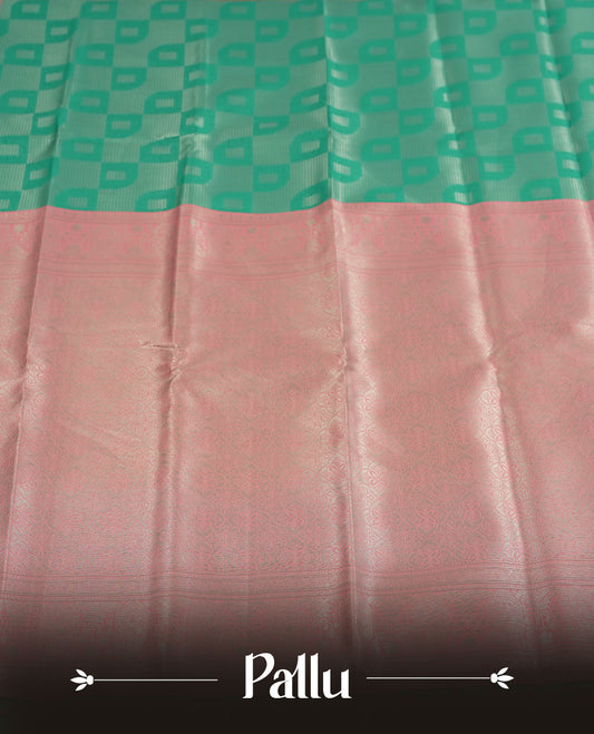 aqua green colour semi silk saree adorned with silver zari designs on the body, complemented by a contrasting pastel pink border and pallu, and paired with a matching blouse piece.