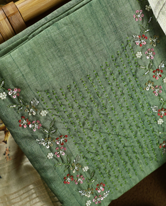 Light green colour churidhar material adorned with floral embroidery and sewn glass beads on the yoke, paired with a plain green bottom and a beige dupatta featuring floral prints.