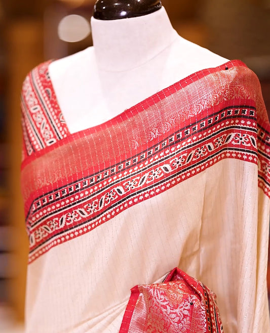 Beige Dolla silk saree featuring antique zari stripes across the body, adorned with a striking Ajrak and Traditional red colour border, ajrak printed pallu and paired with a perfectly matching blouse.