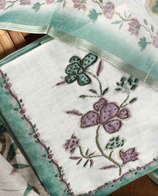 Beige & Sea green colour churidhar material with floral print enhanced by sewn glass beads on the body, paired with plain lavender bottom & floral print dupatta.