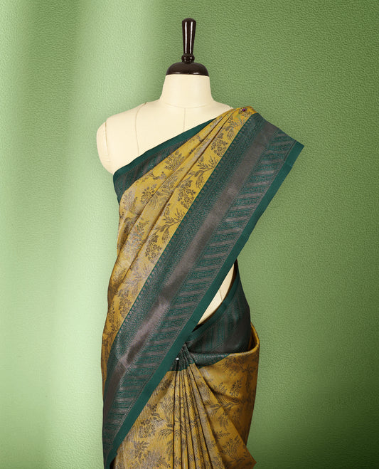 Deep Mustard colour semi silk saree featuring neem zari floral kodi motifs all over the body, complemented by a rich green woven border with geometric detailing, with matching blouse.