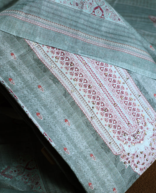 Pastel green colour churidhar material with intricate thread embroidery and sequin highlights, paired with a plain matching bottom and a soft printed dupatta for a subtle yet elegant ethnic ensemble.