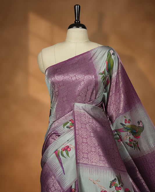 Purple Colour semi tussar Banarasi saree featuring vibrant multi-color floral prints across the body, with shimmering geometric zari patterns, and a matching blouse detailed with silver woven buttas.