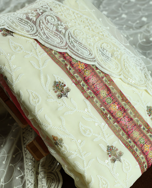 Cream colour churidhar material with heavy embroidered majenta neck work, delicate floral motifs on the body, and multicolor panel detailing & Comes with matching plain bottom and embroidered net dupatta.