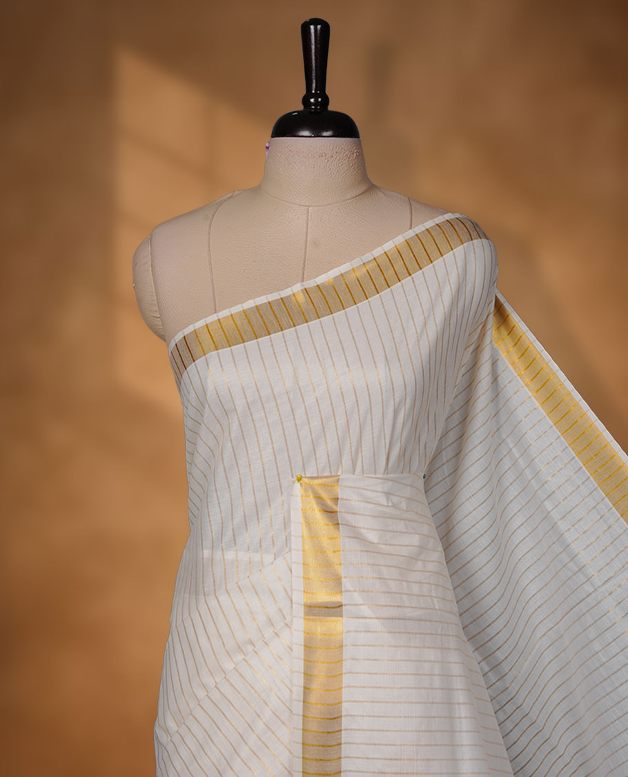 Off-white colour cotton Kerala saree featuring fine golden stripe detailing across the body, highlighted by a rich gold kasavu border along the edges and pallu, and paired with a matching striped blouse.