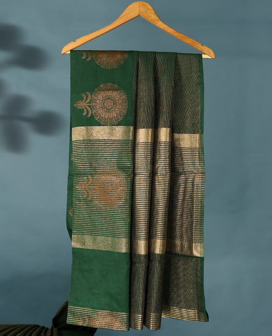 Bottle green Colour Semi Tussar Silk saree featuring golden zari horizontal lines across the body, adorned with bold floral motifs on the border, paired with a matching blouse.