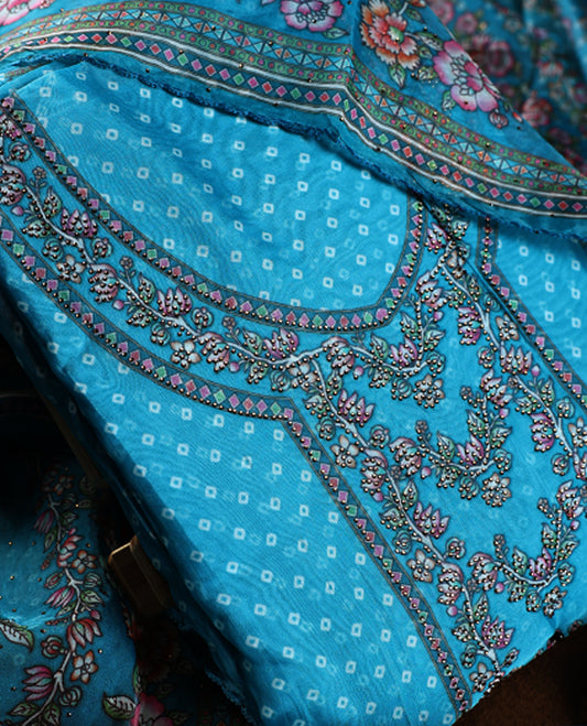 Turquoise blue churidhar material adorned with delicate floral, stone and vine prints, enhanced by a contrast border & Paired with a plain matching bottom, perfect for festive wear and casual elegance.