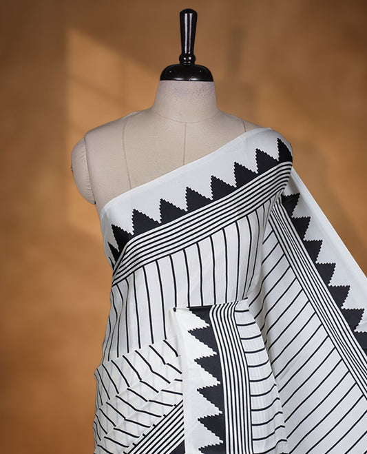White colour semi modal saree highlighted with black triangle border accents and sleek striped detailing across the drape, featuring a bold oversized black circular motif on the pallu, paired with a matching printed blouse.