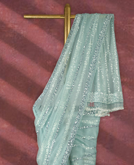 Pastel mint green colour net designer saree adorned with shimmering sequin stripes all over and a sequin embellished border with beaded tassel detailing on the pallu, paired with a matching worked blouse for a chic festive look