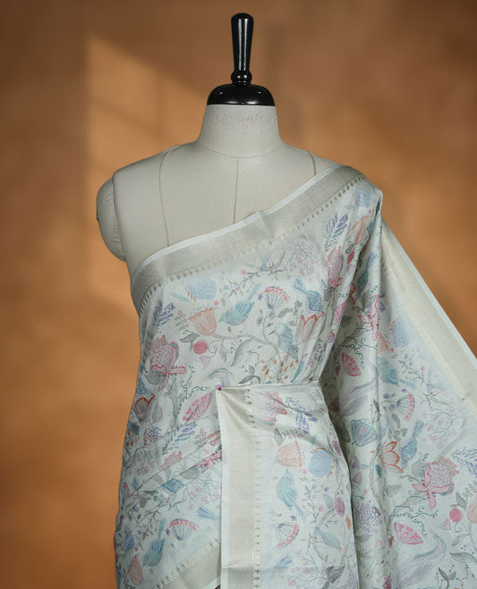 Powder blue colour semi tussar silk saree featuring all over floral and leaf motifs on the body with a subtle self border and tasselled pallu, paired with a matching blouse.