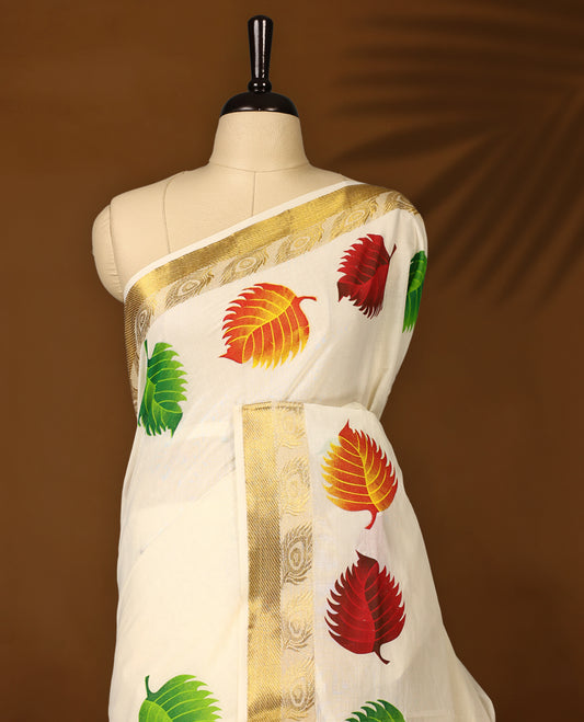 Elegant off white cotton Kerala saree adorned with vibrant multicolor leaf motifs, highlighted by a rich golden zari border and pallu paired with matching blouse.