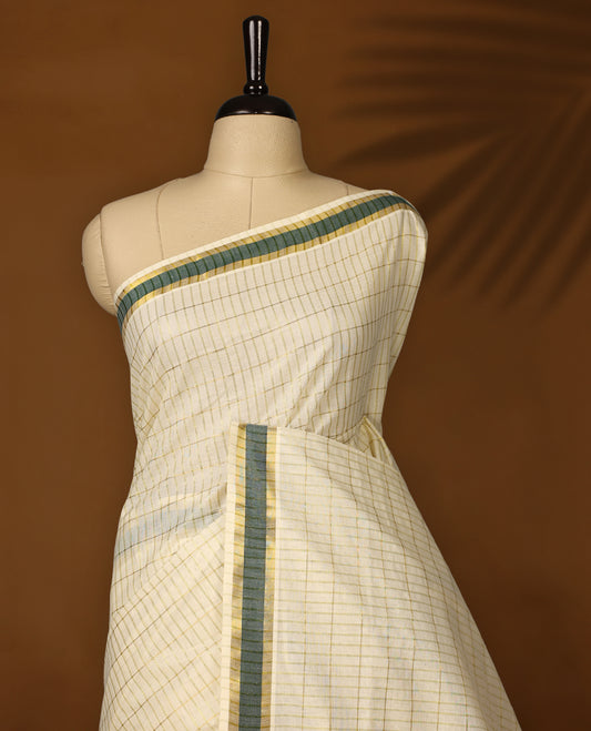 Elegant off white colour cotton Kerala saree featuring subtle golden checks, green & gold zari border, and rich striped pallu with tassels, offering a classic, graceful look &Pair with a matching blouse for charm.