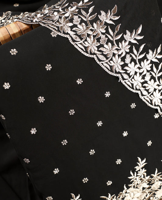 Black colour churidhar material beautifully designed with golden floral embroidery, thread highlights, paired with a plain matching bottom and an elegant embroidered dupatta.