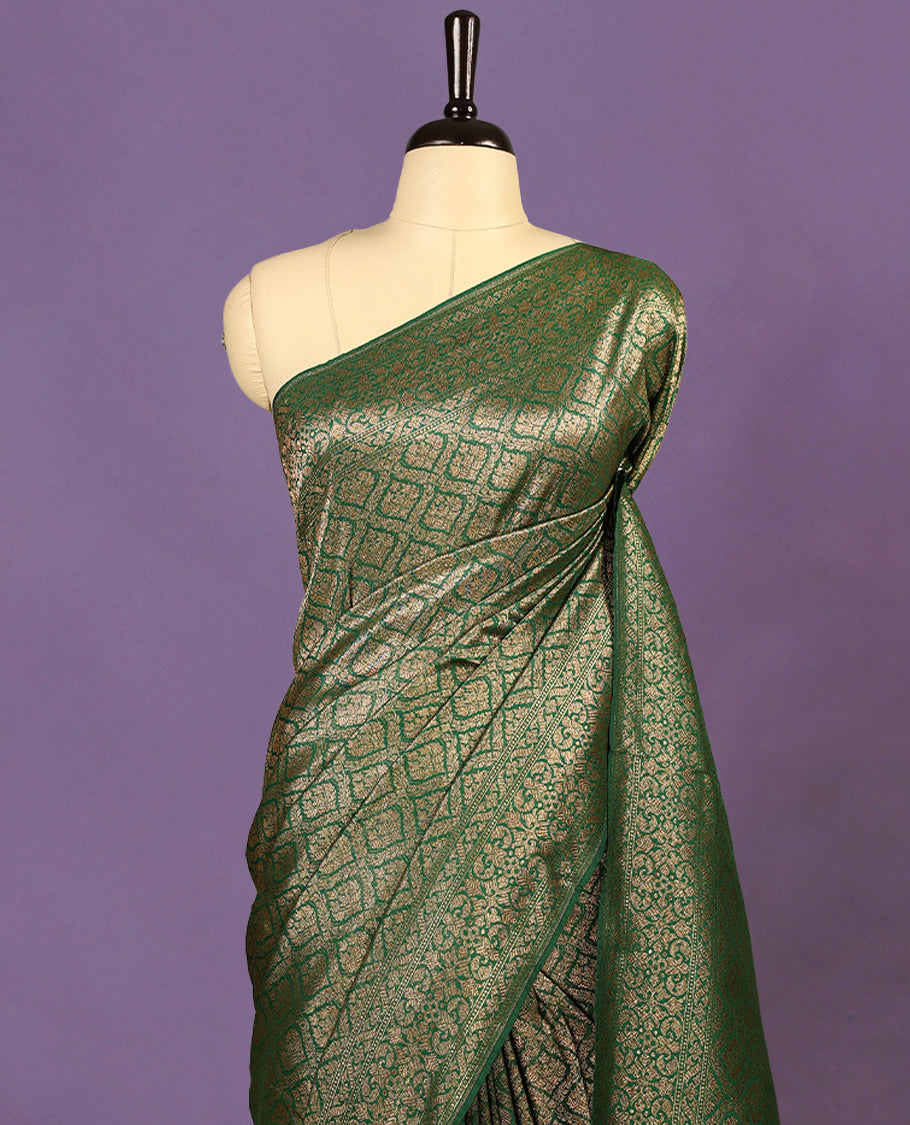 Green colour semi Banaras Katan saree featuring an antique Gold zari jacquard body, complemented by a self colour traditional border with a floral kodi design, paired with a matching blouse