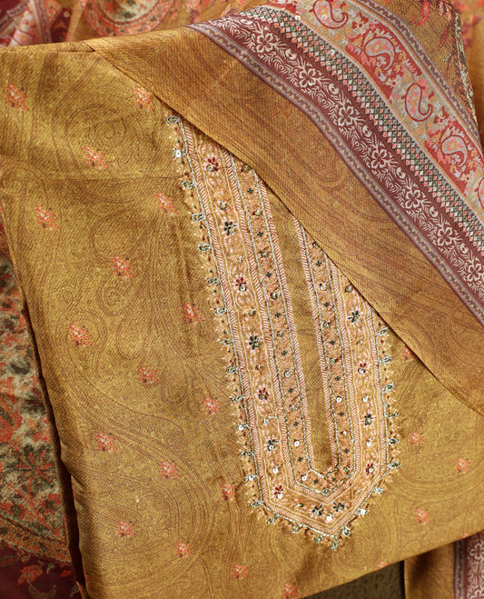 Dark ochre yellow colour churidhar material featuring intricate paisley prints and delicate embroidery with stone highlights, paired with a plain matching bottom and a printed dupatta.