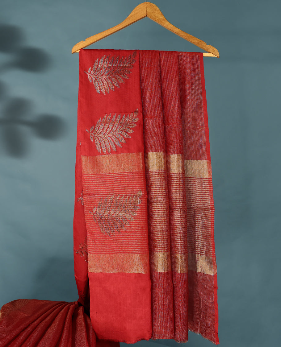 Red Colour Semi Tussar Silk saree featuring golden zari horizontal lines across the body, adorned with bold Leaf motifs on the border, paired with a matching blouse.