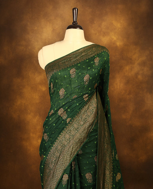 Deep green colour Banarasi Bandhani silk saree featuring light parrot green hand Bandhani patterns with intricate Banarasi motifs, complemented by antique zari woven border and grand pallu, paired with matching antique zari brocade blouse.