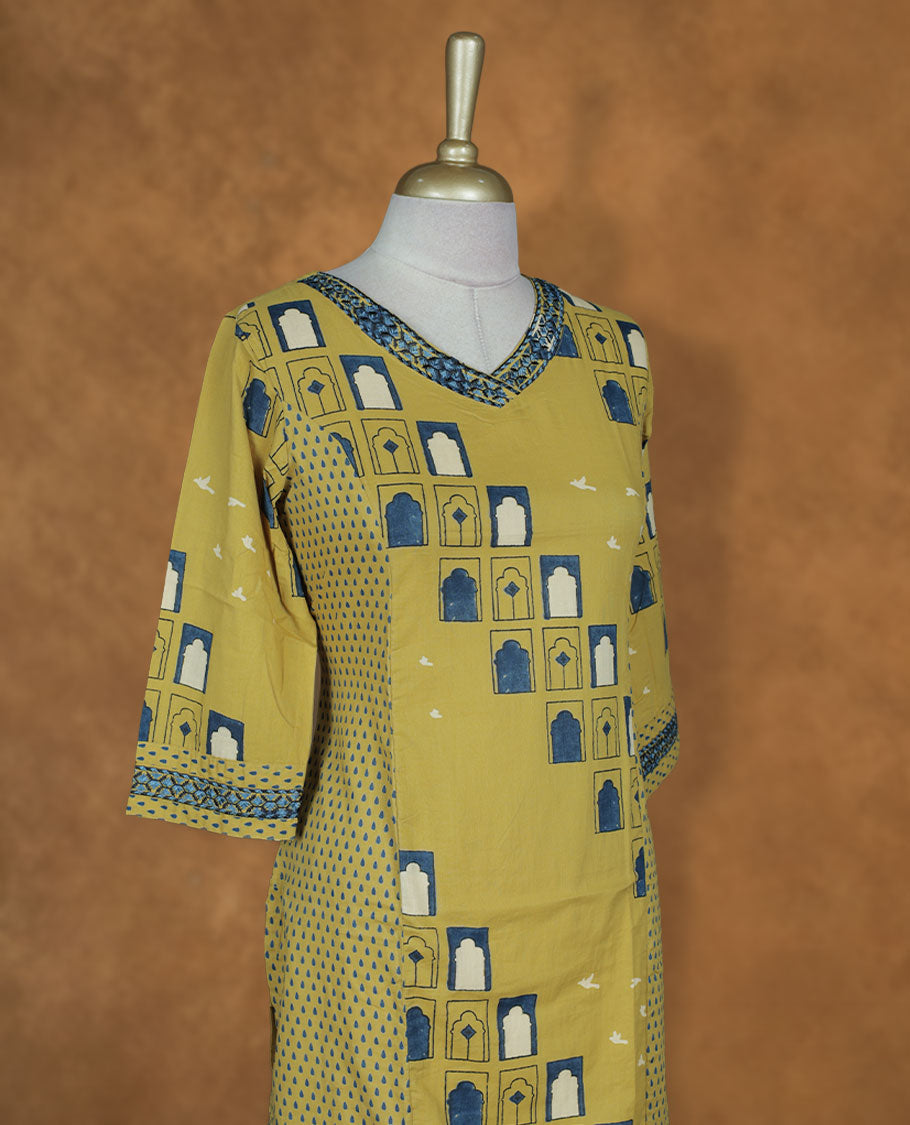 Mustard yellow colour printed kurti by Talisha with V neckline, geometric window motifs in blue and white, straight calf‑length silhouette, and three‑quarter sleeves with contrast printed borders.