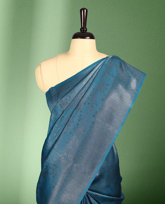 Deep Teal colour semi silk saree featuring neem zari floral kodi motifs all over the body, complemented by a rich self colour woven border, with matching blouse.