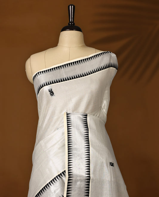 Elegant Tissue Kerala saree in off white colour featuring bold black paisley & floral motifs, woven on a sleek striped body with a striking black kasavu border and Paired with a matching blouse, perfect for festivities.