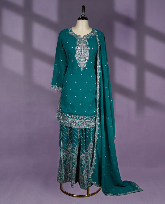 Teal green colour sharara set featuring a notched round neckline, three quarter sleeves, exquisite silver embroidery, flared embroidered bottoms, and a matching embellished dupatta