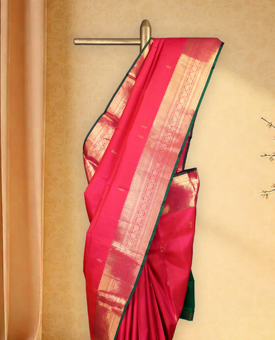 Rani pink pure Kancheepuram saree with gold zari paisley motifs on the body traditional border with floral kodi pattern and green piping, grand pallu with diamond motifs paired with matching blouse