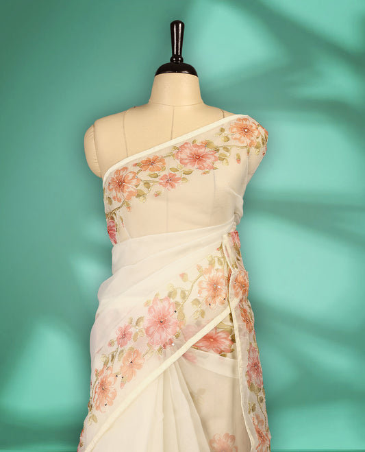 Ivory white colour organza saree adorned with Peach floral print with thread detailing on the border and pallu, in a sheer finish that adds elegance, paired with a matching blouse for a graceful look.