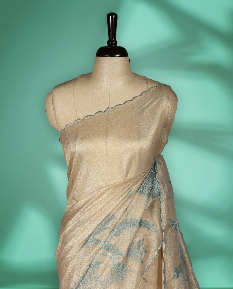 Champagne beige colour organza designer saree featuring subtle woven texture on the body, adorned with soft Blue floral embroidery along the border and pallu, finished with scalloped Thread edging paired with matching blouse.