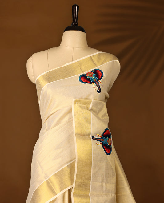 Light Gold colour Tissue Kerala saree featuring Elephant prints on body and a beautifully woven Gold Kasavu border, paired with a matching blouse perfect for festive occasions.