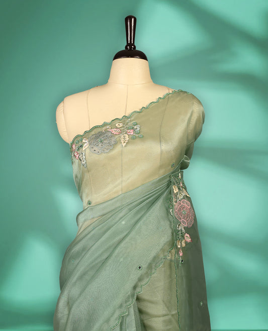 Pastel Green Colour organza saree featuring delicate floral embroidery with applique, bead, mirror, and thread detailing on the body and scalloped border, lending a soft feminine charm, paired with a matching blouse.