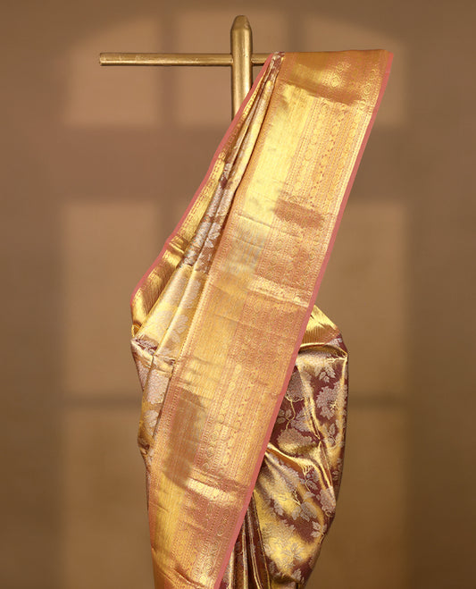 Golden Colour Kancheepuram tissue silk saree adorned with intricate silver and gold zari floral work on the body, elegantly accentuated by a pastel peach traditional Chakkram and floral design border, and paired with a matching blouse.