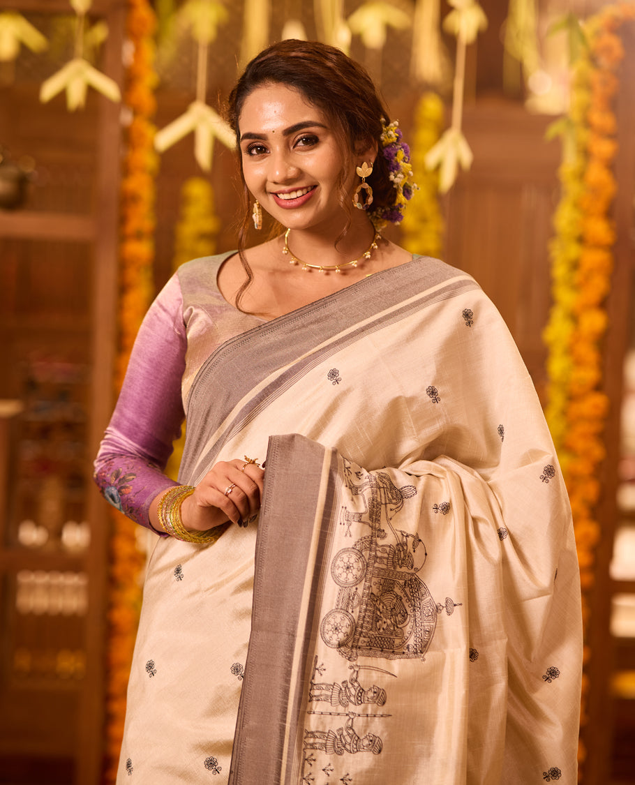 Off White colour Tussar saree adorned with small black woven motifs across the body, featuring an artistic temple chariot motif on the pallu, highlighted with a sleek grey border, paired with a matching blouse
