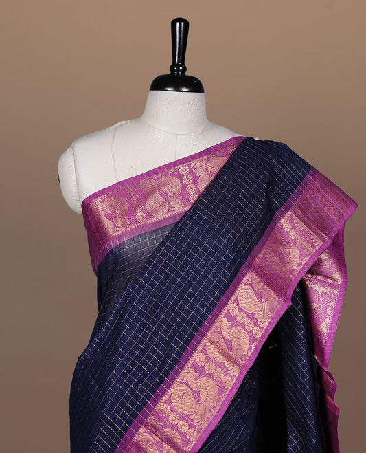 Navy blue colour sungudi cotton saree featuring gold zari check pattern across body, contrast Magenta colour with gold zari peacock and floral pattern on border, without blouse piece.