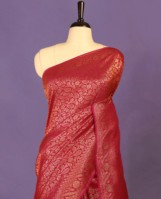 Rani pink colour semi Banaras Katan silk saree featuring intricate Antique Bronze zari floral and vine patterns woven throughout the body, enhanced with a rich traditional border and detailed pallu, paired with a matching blouse piece.