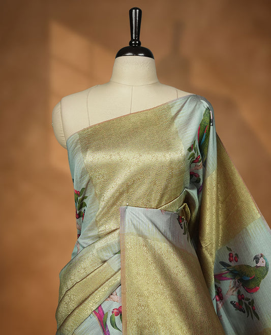Parrot Green colour semi tussar Banarasi saree featuring vibrant multi-color floral prints across the body, with geometric zari patterns, and a matching blouse detailed with silver woven buttas.